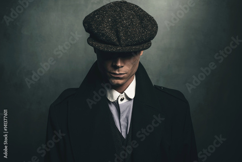 Mysterious portrait of retro 1920s english gangster with flat cap. photo