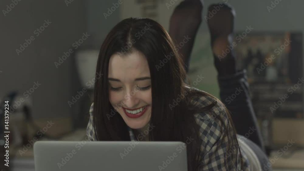 Beautiful girl lying on the bed and looking at a laptop. Beautiful girl lying on the bed and looking at a laptop.