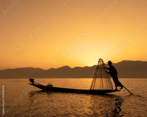 Fisherman silhouette at sunset during evening fishing on Inle lake, Myanmar