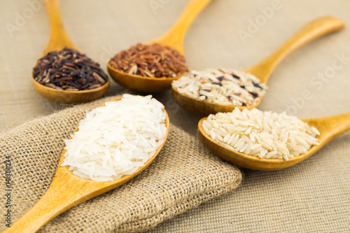 Jasmine rice, Brown rice, Red rice, Mixed rice and Riceberry in wooden spoons.