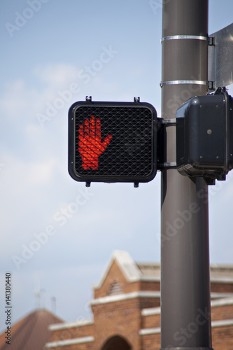 Electronic crosswalk sign with warning hand signal.