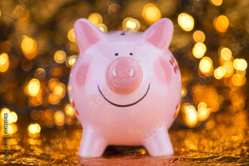 Pink piggy bank with yellow blurred bokeh background.