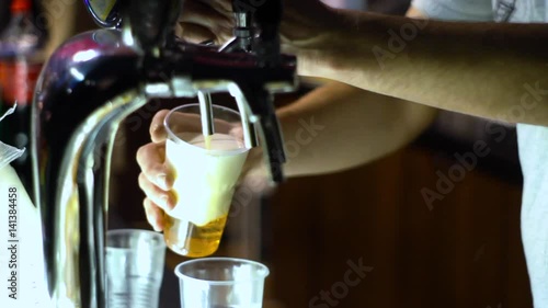 Man drawing beer from tap in an plastic cup. Isolated in a black background photo