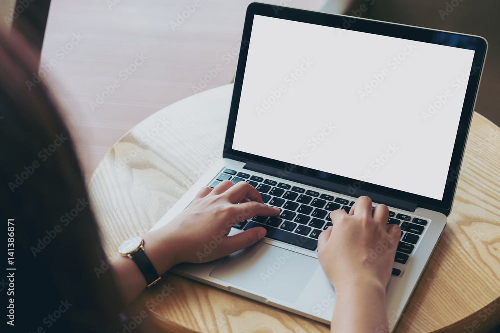 Mockup image of hands using laptop with blank white screen on vintage wooden table in cafe Mockup image of hands using laptop with blank white screen on vintage wooden table in cafe
