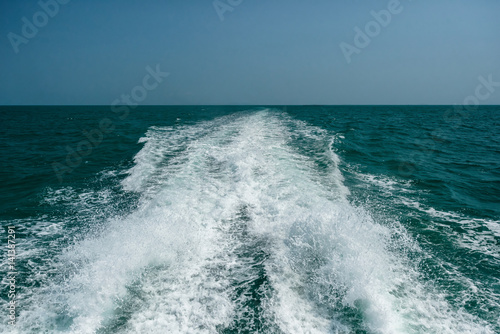 Acting wave behind motor boat at the vast ocean