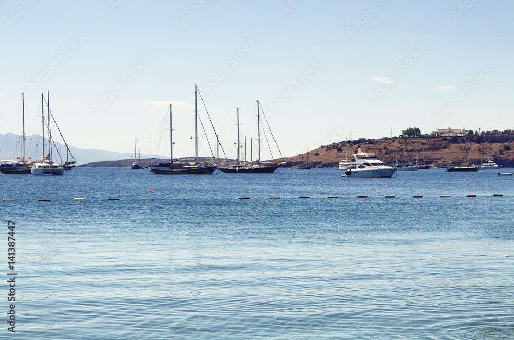 Luxury yachts (sailing boats) parked on turquoise water in front of Bodrum castle. The image shows Aegean and Mediterranean culture of coastal lifestyle. Luxury yachts (sailing boats) parked on turquoise water in front of Bodrum castle. The image shows Aegean and Mediterranean culture of coastal lifestyle.