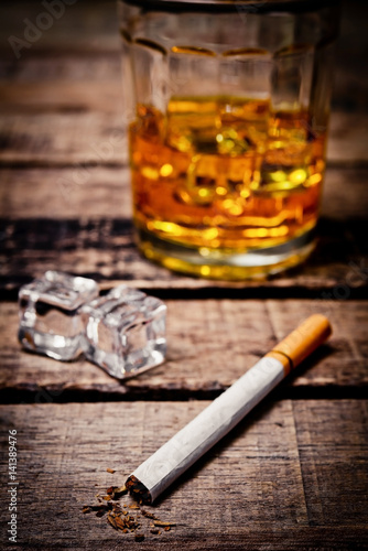 Glass of whiskey and  cigarettes. An old and vintage countertop with highlight and a glass of hard liquor