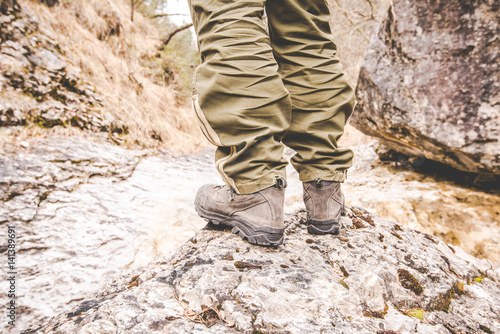 close up of trekking legs and boots - hiker exploring a little creek - wanderlust travel concept with sporty people at excursion in wild nature - outdoor activity Italy