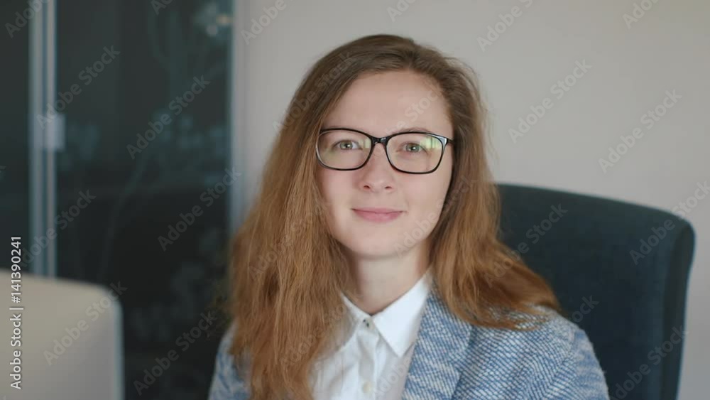 Portrait of smiling young businesswoman at modern startup business office interior. close up slow motion Portrait of smiling young businesswoman at modern startup business office interior. close up slow motion