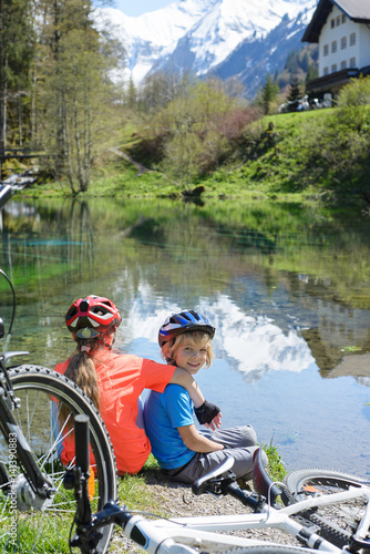 Happy children riding a bike on the lake in a beautiful mountain landscape.