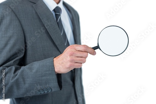Mid section of businessman holding magnifying glass