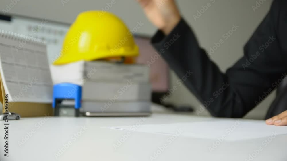 Hands of woman using subber stamp to white paper in office with yellow engineer hat on table Hands of woman using subber stamp to white paper in office with yellow engineer hat on table