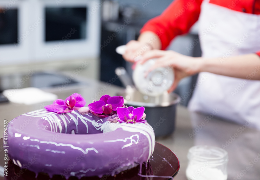 The confectioner prepares a gentle purple lilac violet mass cake with orchids The confectioner prepares a gentle purple lilac violet mass cake with orchids