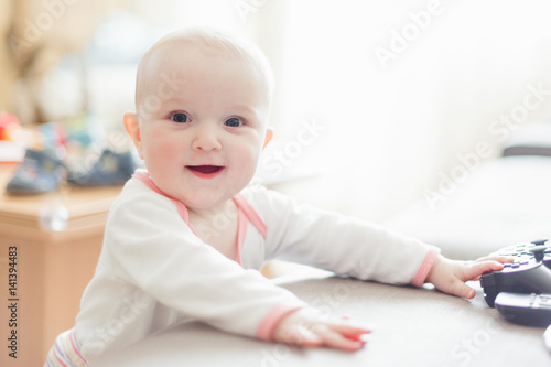 A baby is standing leaning on a sofa