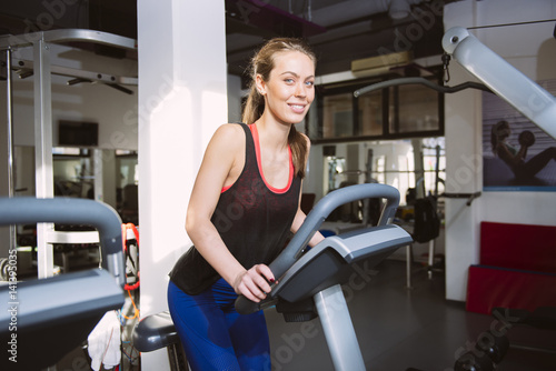 Smiling woman riding an exercise bike in gym © BGStock72