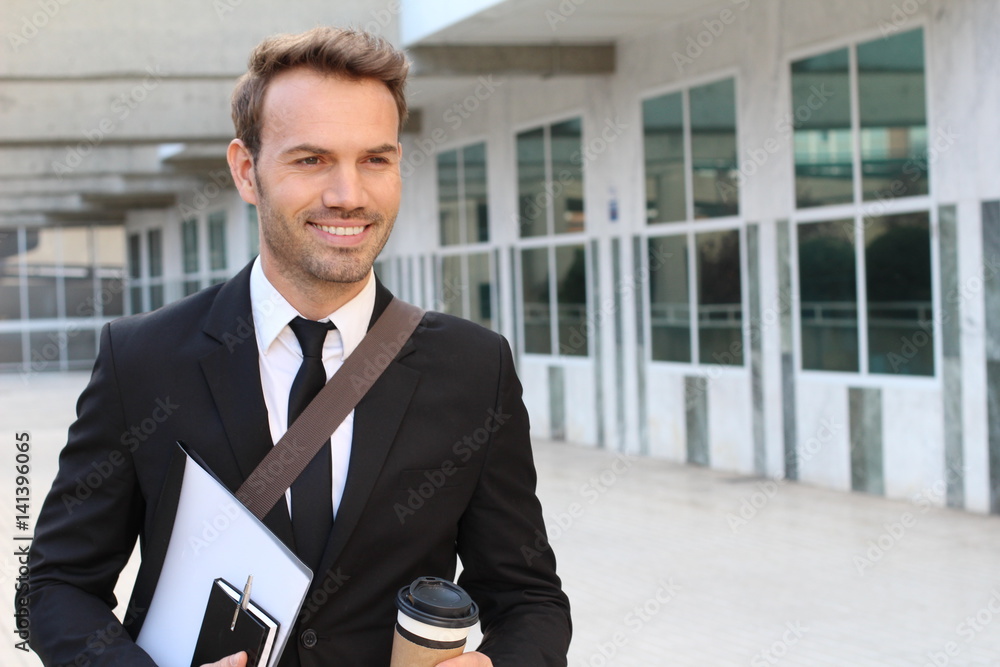 Smiley businessman walking outside the office building Smiley businessman walking outside the office building