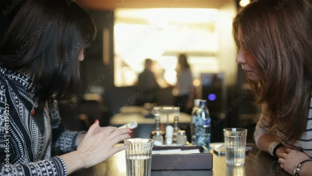 Two young women eating and talking in a cafe Two young women eating and talking in a cafe
