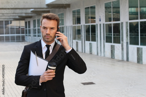 Focused businessman walking during phone call outdoors © ajr_images