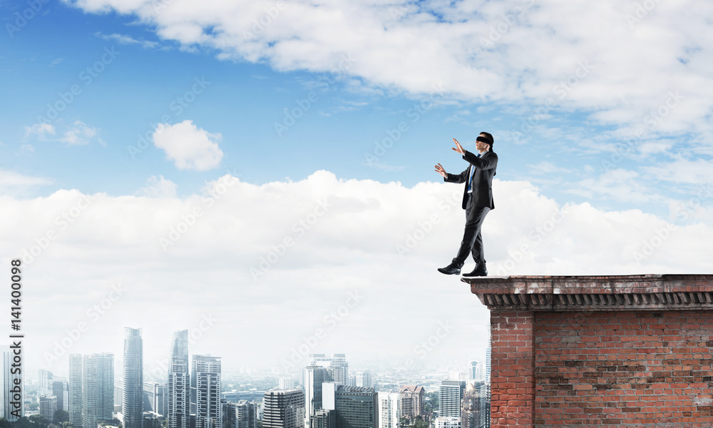 Danger and risk concept with businessman making step from edge Danger and risk concept with businessman making step from edge