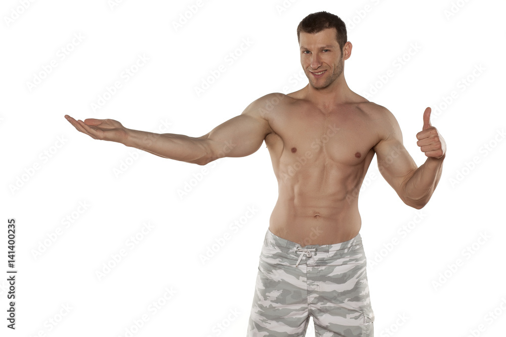half-naked handsome and muscular young man holding imagunary object on a white background