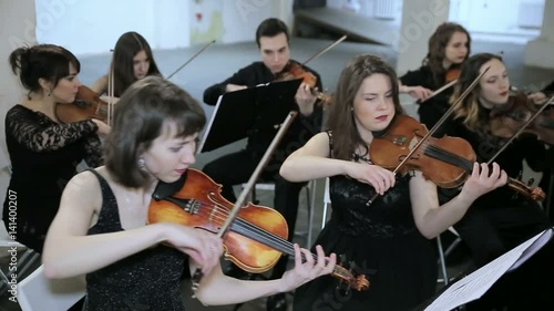 Orchestra. Musician playing violin on the symphony hall photo