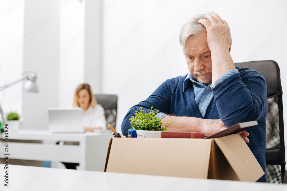Upset office worker gathering belongings into the box Upset office worker gathering belongings into the box