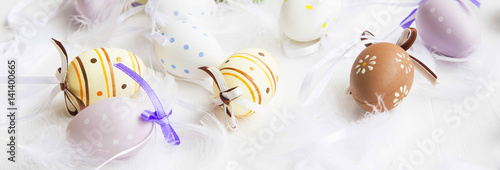 Easter eggs with feathers on white painted wooden background