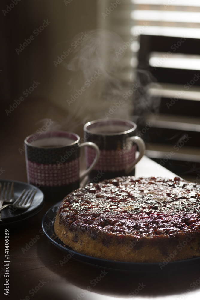 Cranberry upside-down cake on plate, hot drinks on table beside cake Cranberry upside-down cake on plate, hot drinks on table beside cake