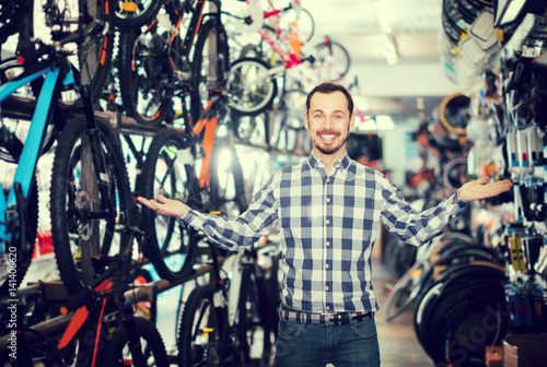 interested man in bicycle shop chooses for himself sports bike