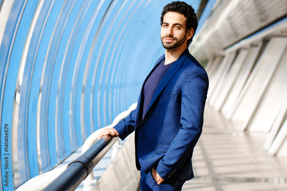 Portrait of Arab man in a suit holds onto the railing in glass transition Portrait of Arab man in a suit holds onto the railing in glass transition