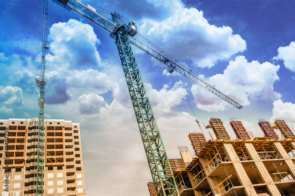 Construction crane above buildings under the clouds Construction crane above buildings under the clouds