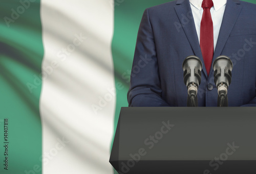 Businessman or politician making speech from behind a pulpit with national flag on background - Nigeria photo