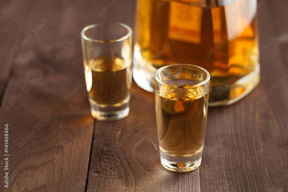 gold tequila in a glass on a background of bright lights. Traditional Mexican drink. gold tequila in a glass on a background of bright lights. Traditional Mexican drink.
