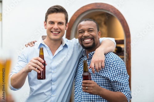 Friends hugging each other while holding beer bottles