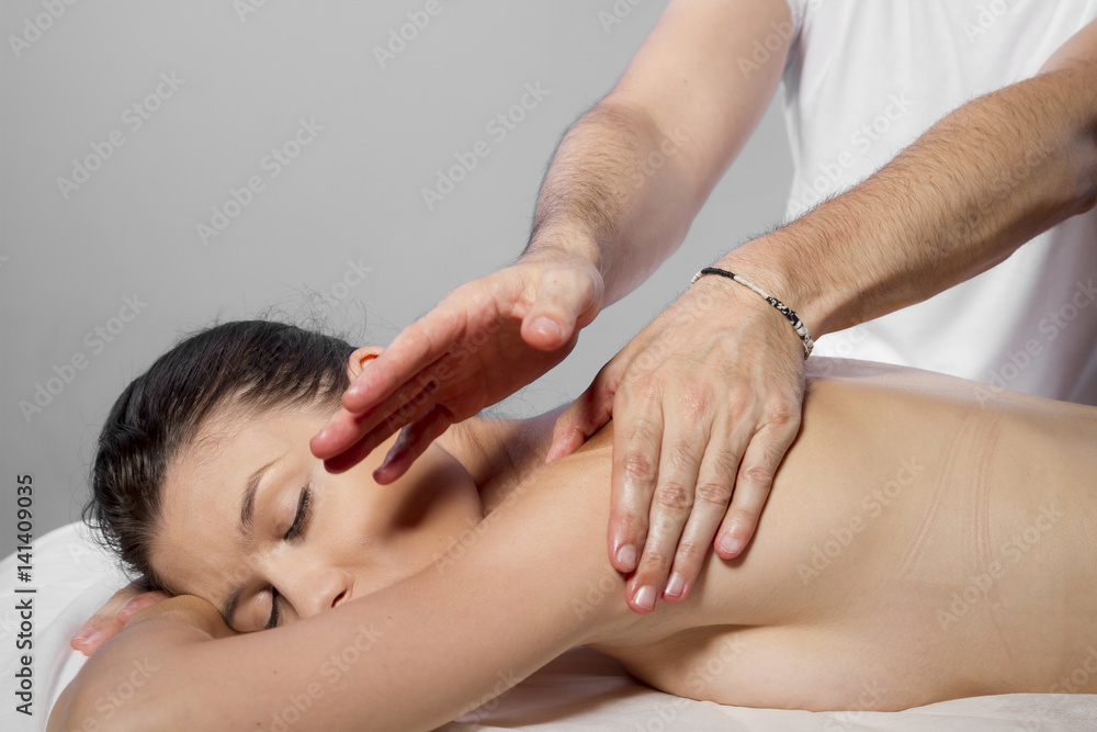 Hands and relaxation, beautiful brunette woman relaxing on a stretcher receiving a therapeutic massage from hands of a professional masseuse
