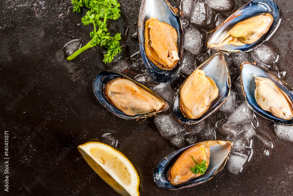 Prepared for cooking dinner seafood - fresh opened mussels on ice, on black concrete table, with lemon and seasonings. Top view, copy space Prepared for cooking dinner seafood - fresh opened mussels on ice, on black concrete table, with lemon and seasonings. Top view, copy space