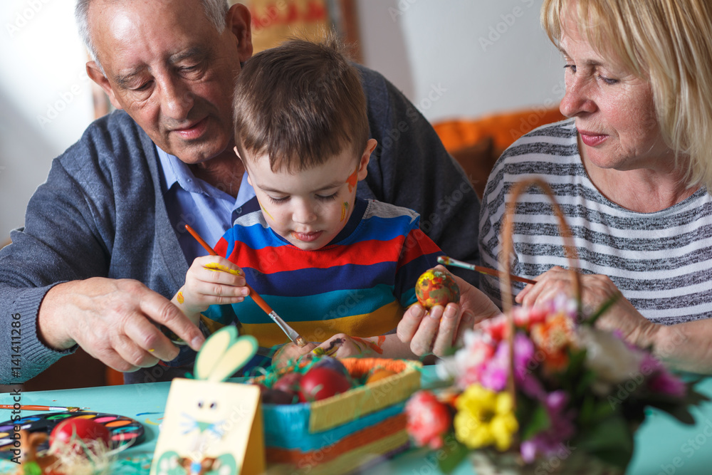 Naklejka premium Grandmother and grandfather with grandson preparing eggs for Easter.