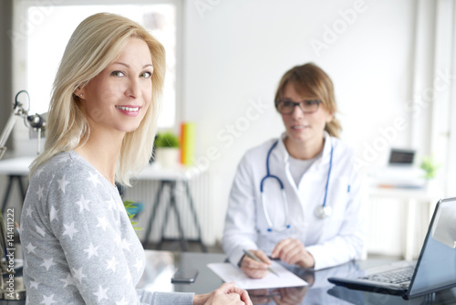 Doctor and her patient. Shot of a middle aged female doctor sitting in front of laptop and consulting with her patient.