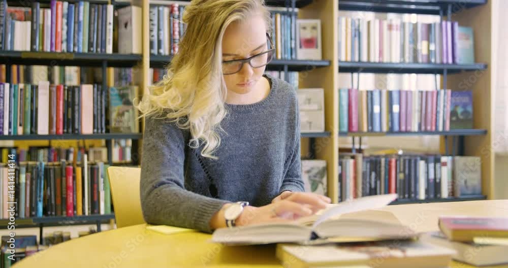 Focused female student with glasses working in the school library Focused female student with glasses working in the school library