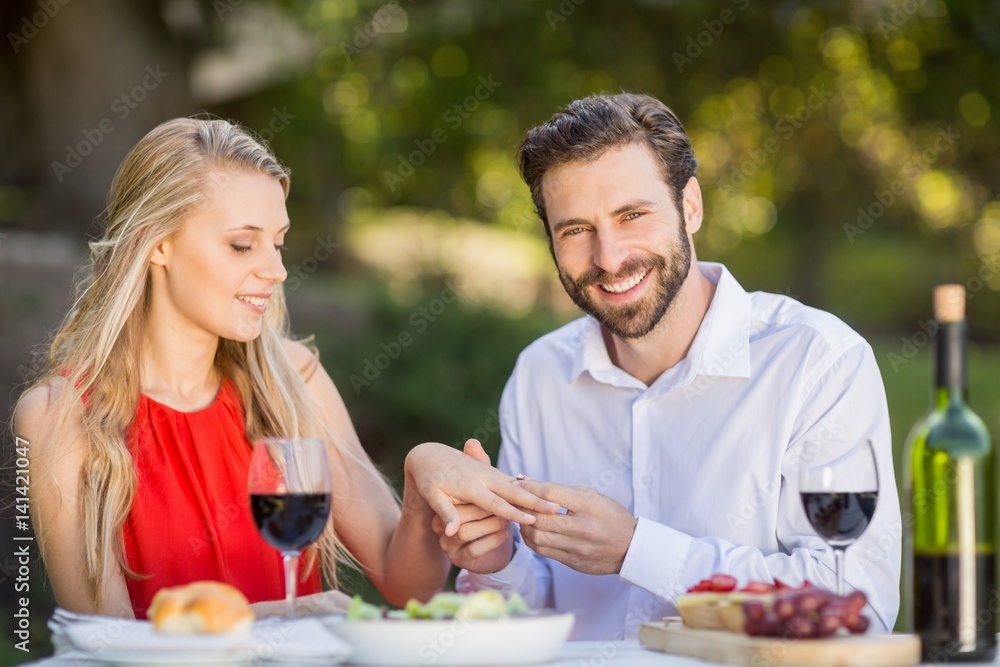 Man putting a ring on womans finger in the restaurant Man putting a ring on womans finger in the restaurant