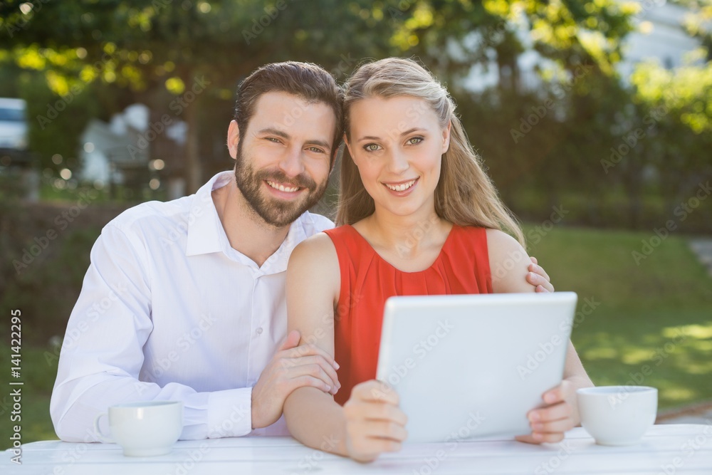 Happy couple smiling while holding digital tablet Happy couple smiling while holding digital tablet
