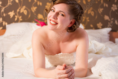 bride in a wedding dress lies on bed