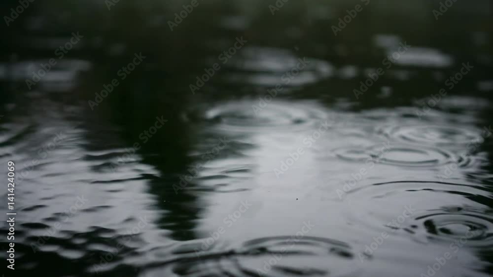 Drops of rain on the water. They create waves and splashes. Slow motion. Looped Drops of rain on the water. They create waves and splashes. Slow motion. Looped