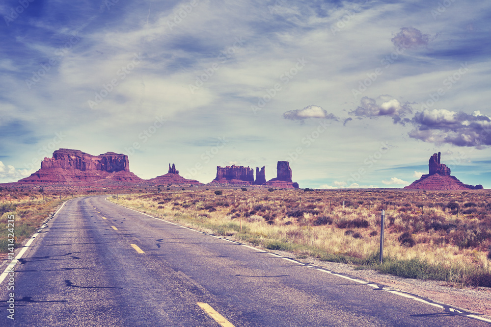 Color toned image of a road towards Monument Valley buttes, travel concept, USA.