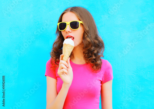 Fashion portrait woman is trying ice cream over colorful blue background