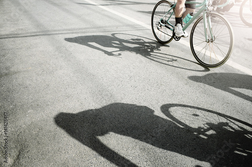 Group of cyclist pedaling on a racing bike with hard shadow in a sunny day.