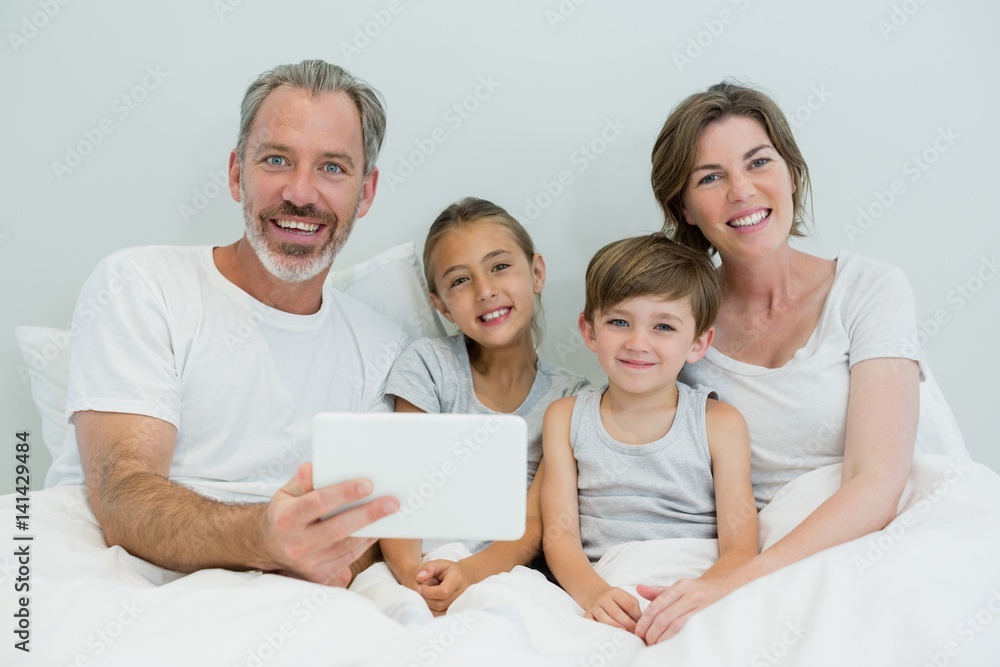 Happy family using digital tablet on bed in bedroom at home Happy family using digital tablet on bed in bedroom at home