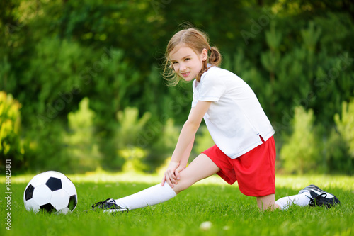 Cute little soccer player having fun playing a soccer game on summer day