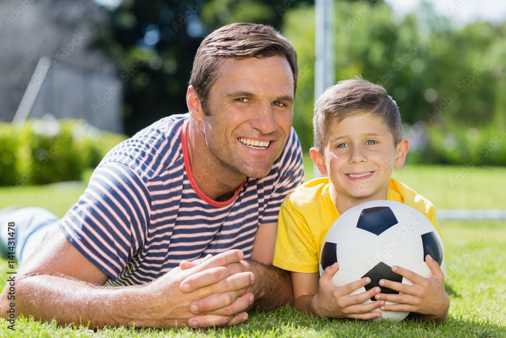 Father and son lying on grass in the park on a sunny day
