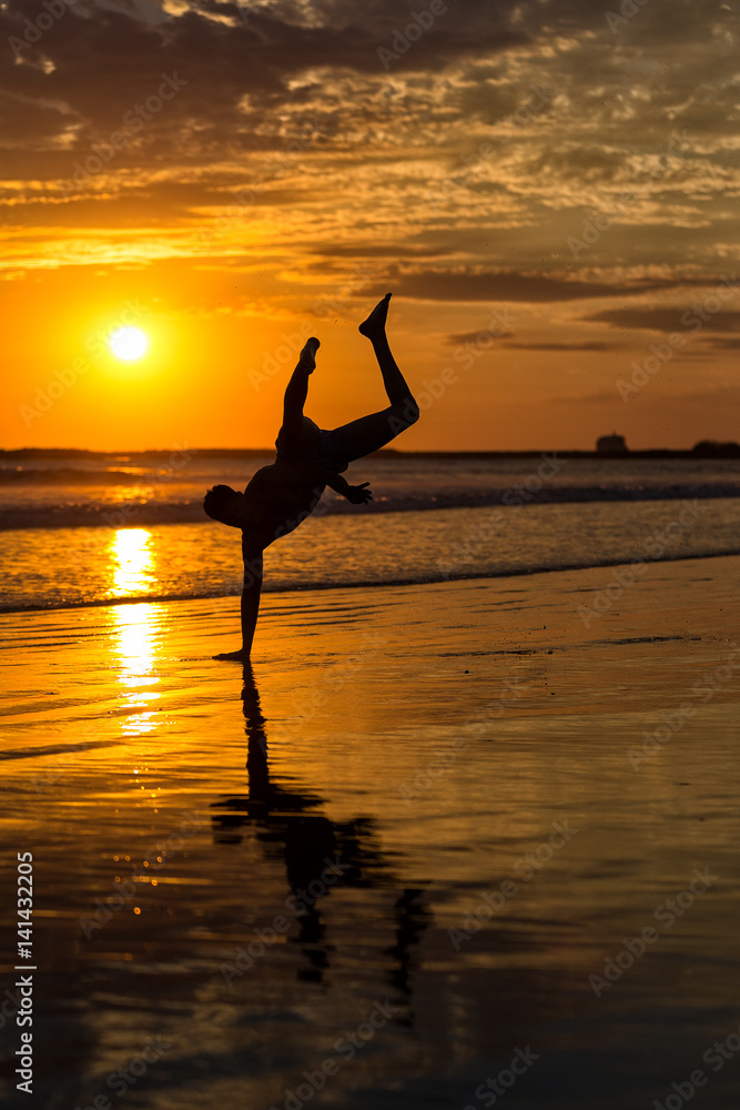 Silhouette of young male capoeira dancer, yoga and martial art specialist at beach in Mexico during spectacular sunset